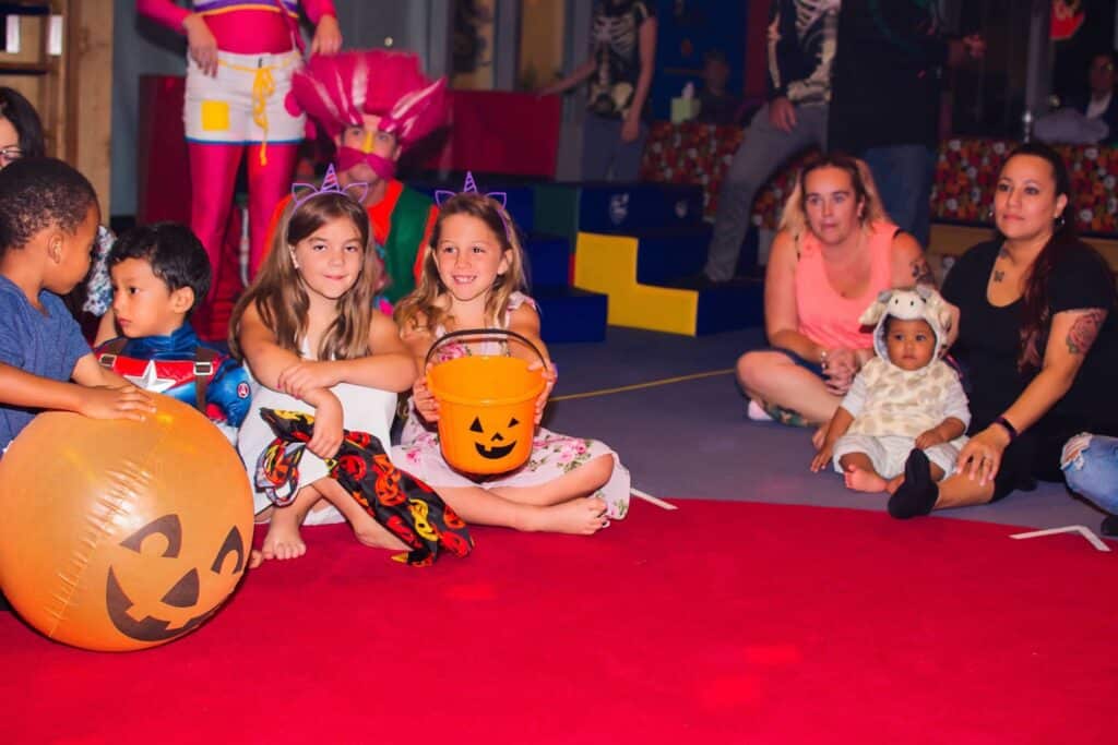 A Kids Party with children sitting on a red carpet.