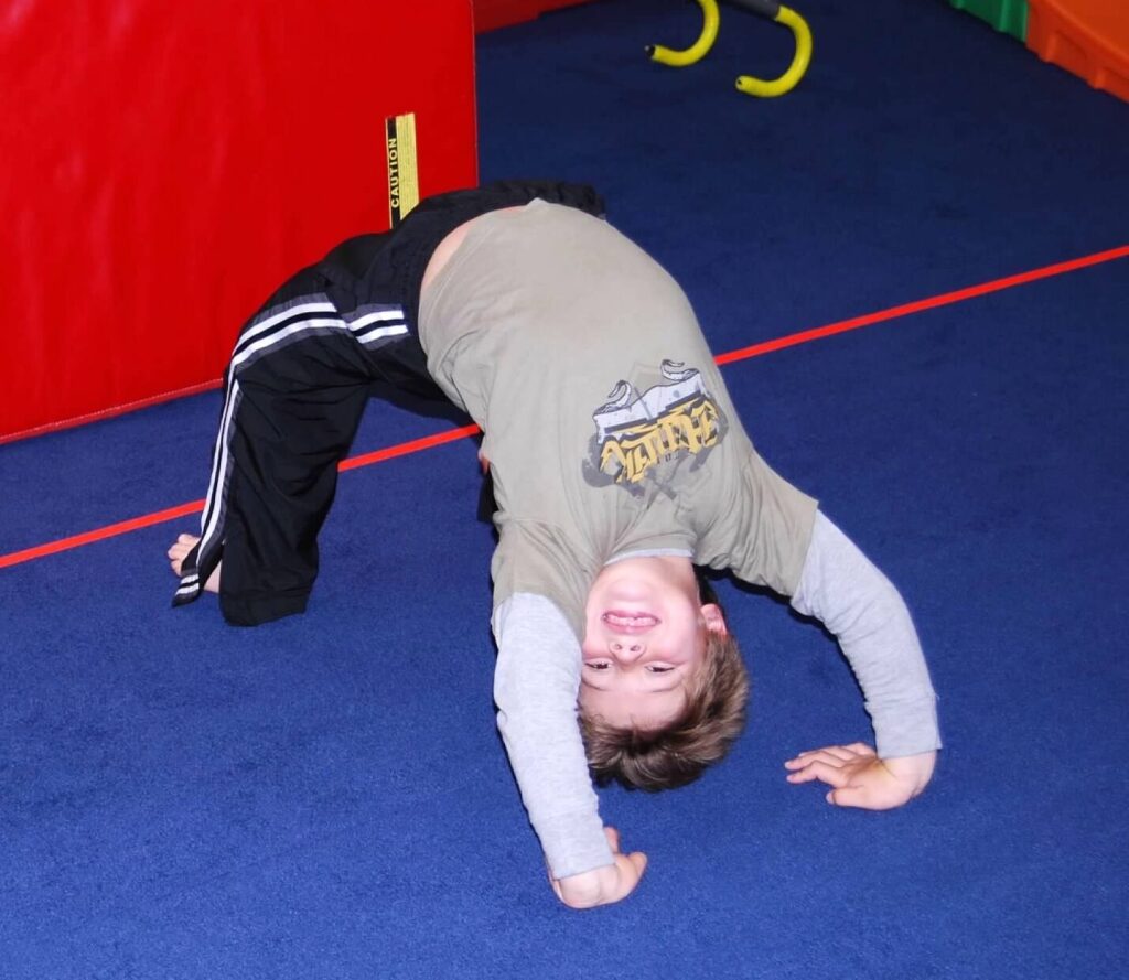 A child is performing a handstand during a fitness class.
