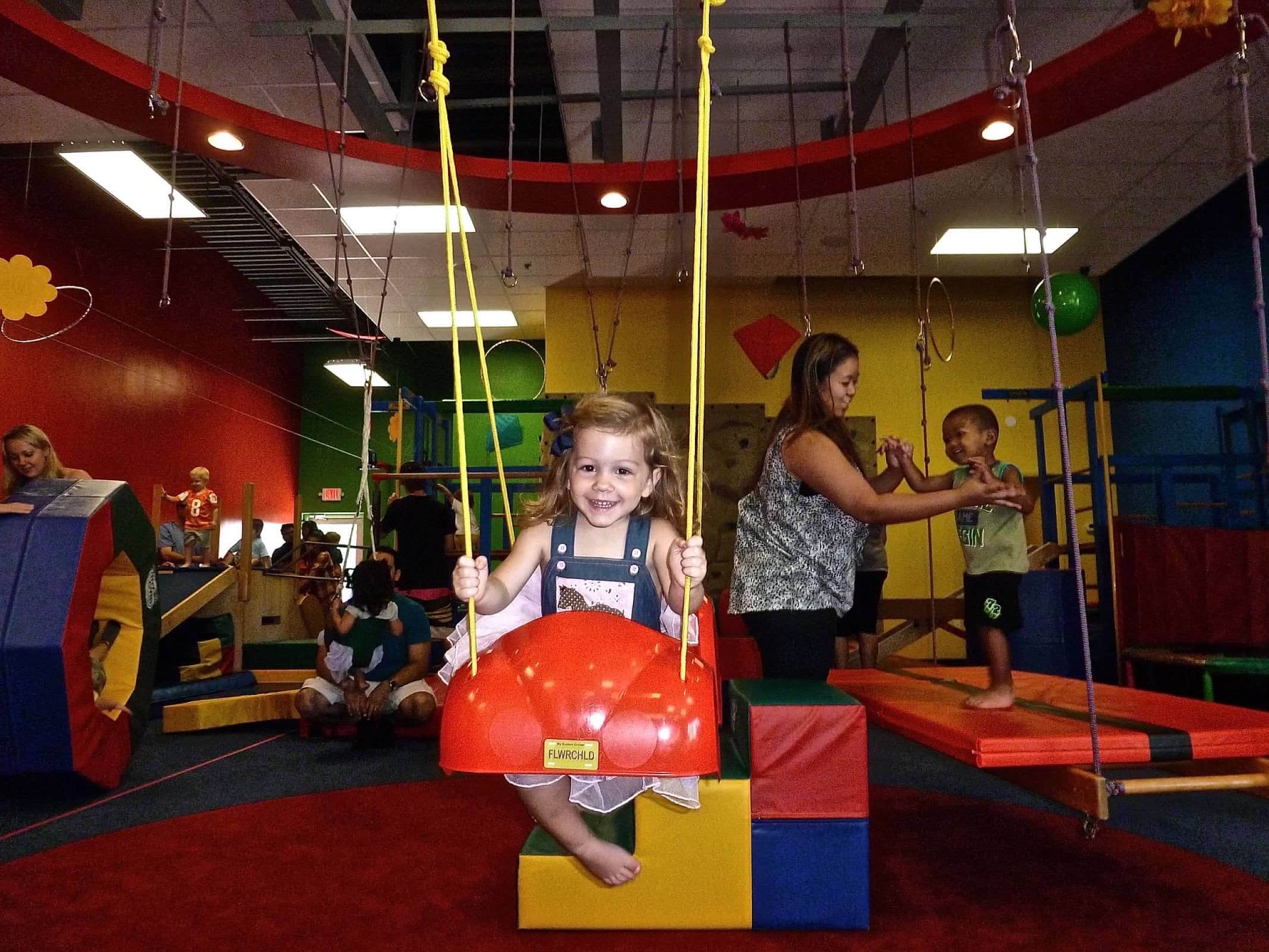 A child playing on a swing in a play room.