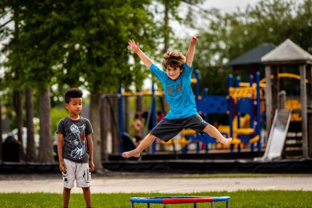 At a Kids Party, one young boy jumps while the other watches.